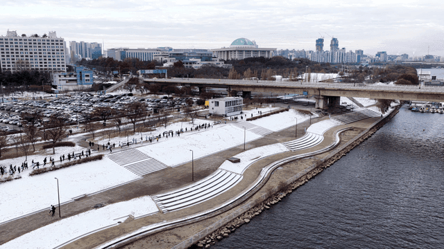 People running on snow-covered path in city park
