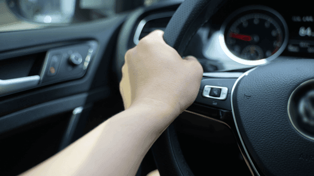 Hands holding car steering wheel