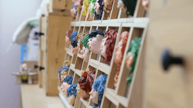 Colorful clay faces displayed on a shelf
