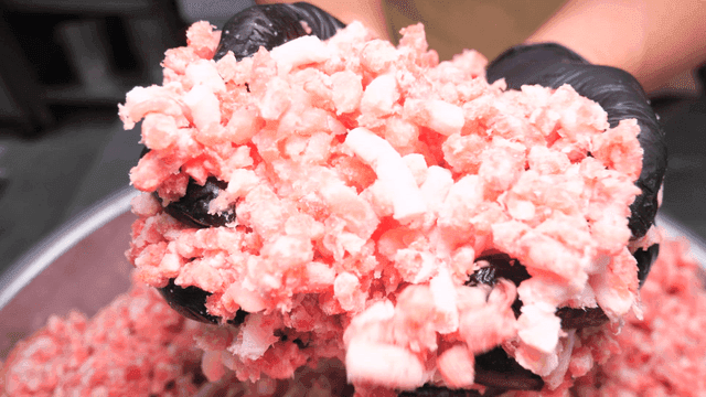 Hand lifting minced meat from large bowl