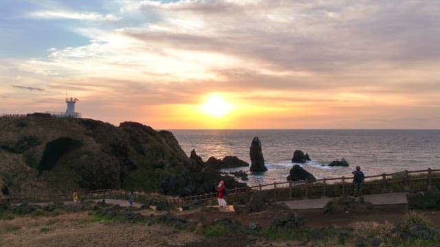 Sunset over a rocky coastline with a lighthouse