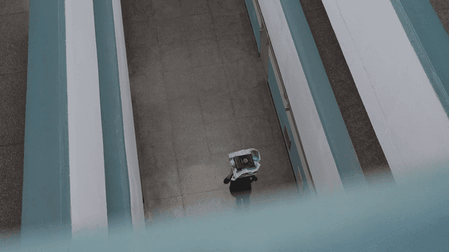Man walking down hallway with tray on his head