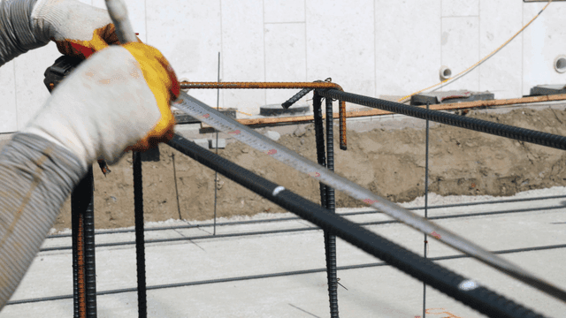 Construction worker measuring rebar