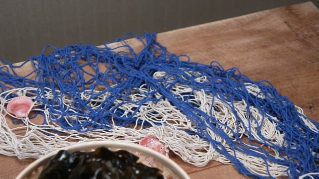 Basket with seaweed and net on wooden table