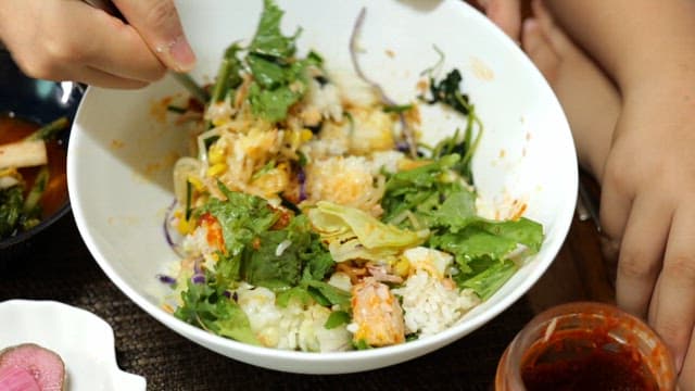 숟가락으로 신선한 채소와 고추장을 슥슥 비벼 만드는 비빔밥