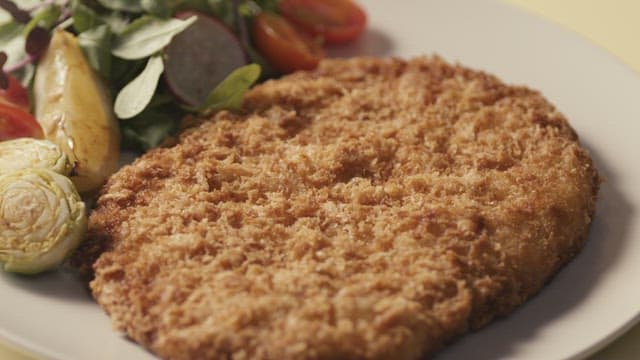 소스가 뿌려지는 돈가스와 신선한 채소 샐러드