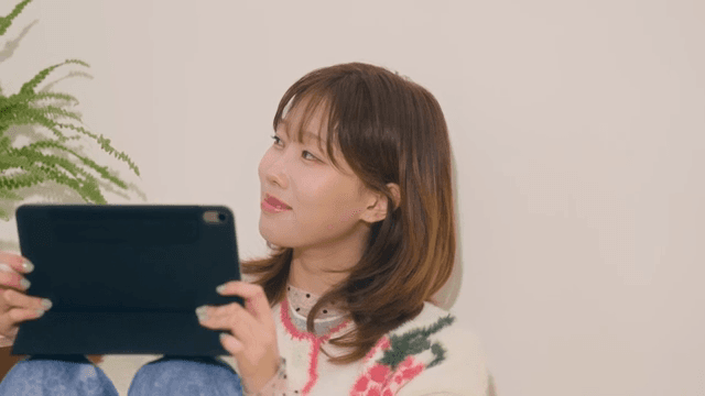 아늑한 방에서 태블릿을 사용하며 창문을 바라보는 여성