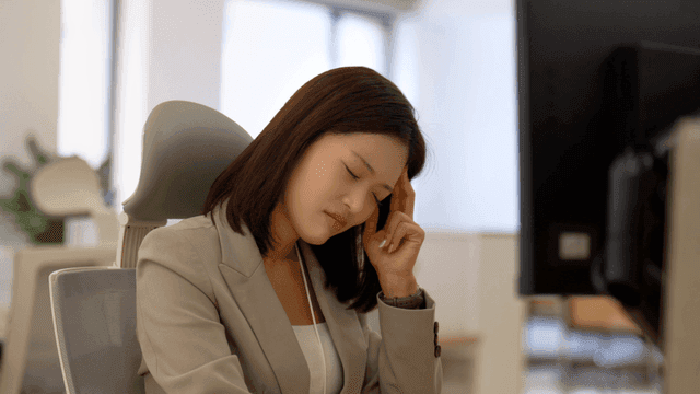 Tired-looking female office worker looking at monitor in office