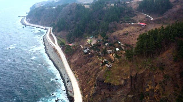 Coastal road winding near cliffside with houses