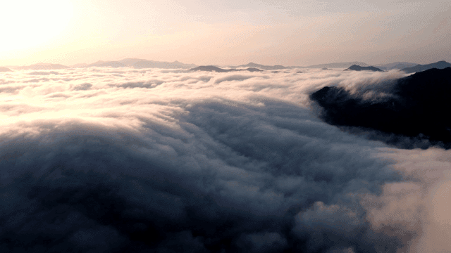 Sunrise illuminating sea of ​​clouds above mountain peaks