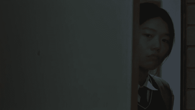교복을 입은 여학생이 어두운 방의 문을 여는 모습