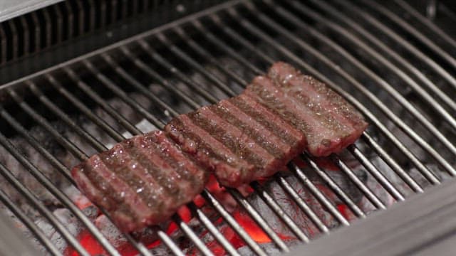 Sizzling Steaks Grilling Over Charcoal