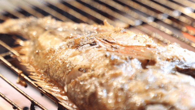 Sizzling grilled fish on barbecue