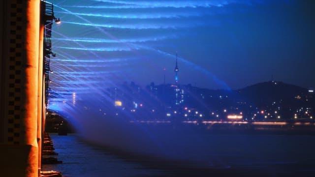 Night view of a bridge fountain with city lights in the background