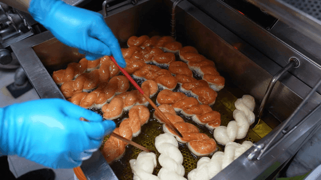 Twisted doughnuts frying in hot oil