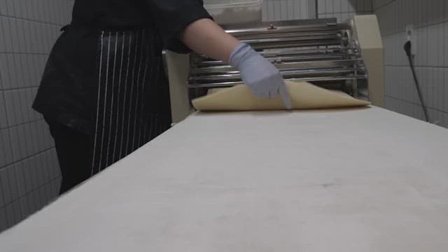 Person using a machine to prepare dough in a factory kitchen