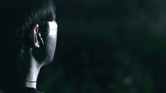 Person listening to music in a dark forest