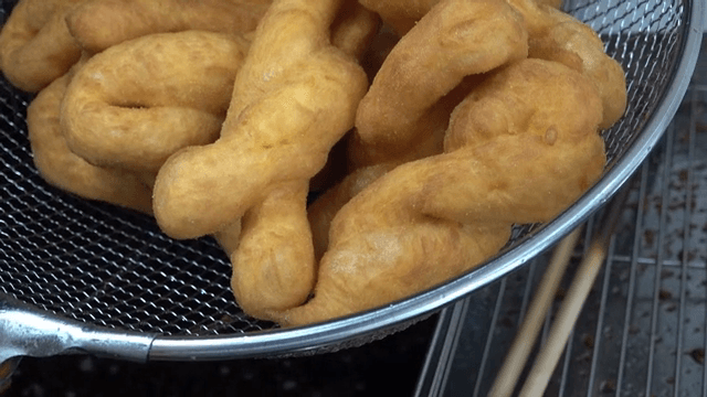 체에 담긴 갓 튀긴 꽈배기 도넛