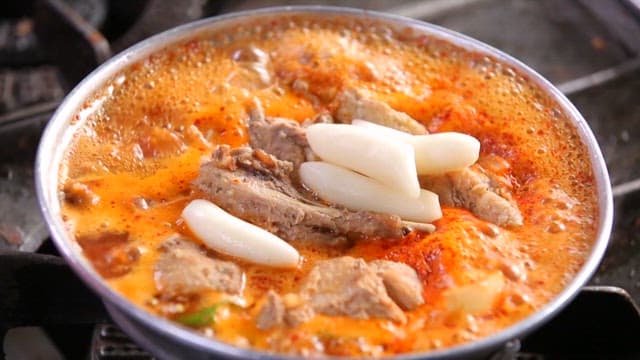 Adding red pepper powder to braised pork ribs with rice cakes