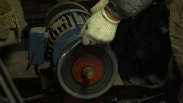 Worker sharpening a blade on a grinder