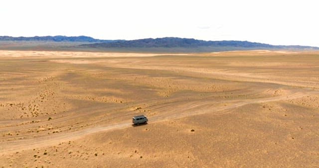 Van traveling through a vast desert