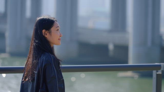 Woman walking by the riverside under a bridge