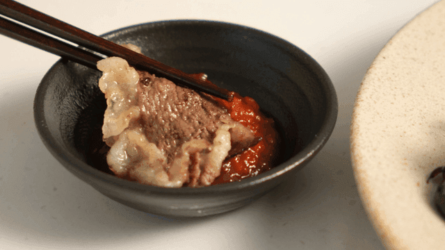Beef dipped in ssamjang with chopsticks
