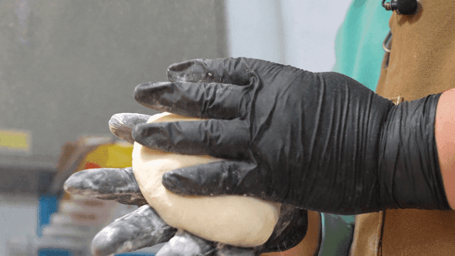 Person kneading dough with flour scattering around