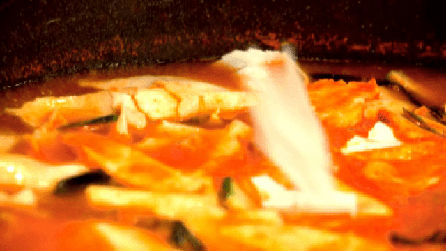 Hands tearing dough into red soup