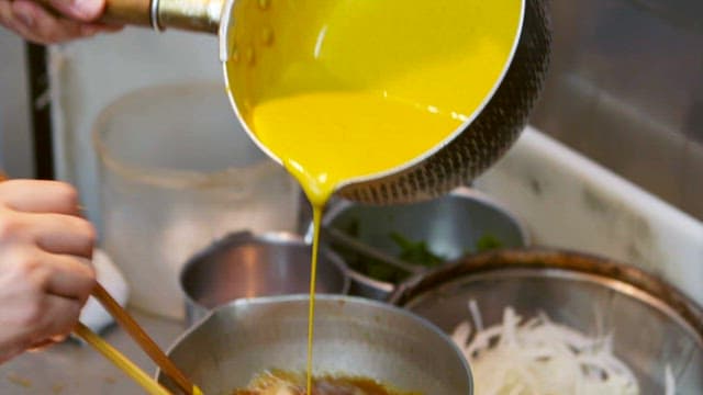 양파가 담긴 끓는 냄비에 계란물을 능숙하게 붓는 모습