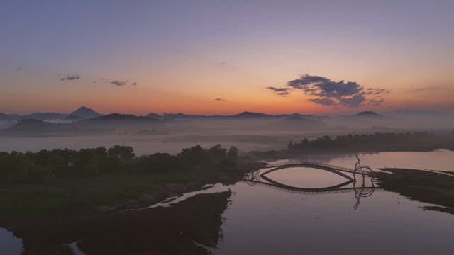 Serene river with misty mountain at sunset