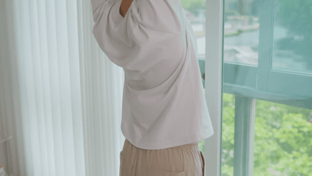 Person Stretching by a Window Overlooking Greenery
