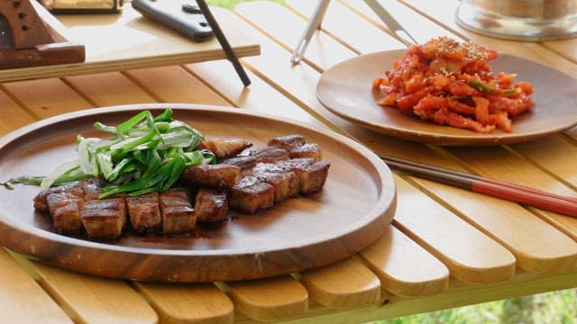 Marinated pork ribs and radish kimchi neatly plated on a wooden table