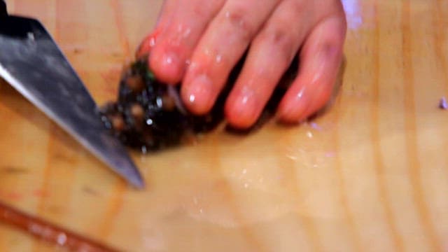 Slicing fresh sea urchin on a wooden cutting board