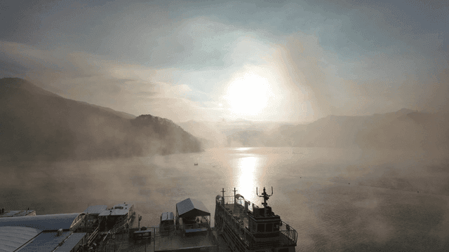 Misty lake with boats at sunrise