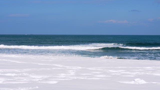 Snow-covered beach with gentle ocean waves