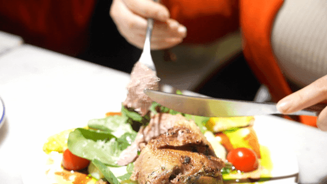 Woman cutting and eating duck confit
