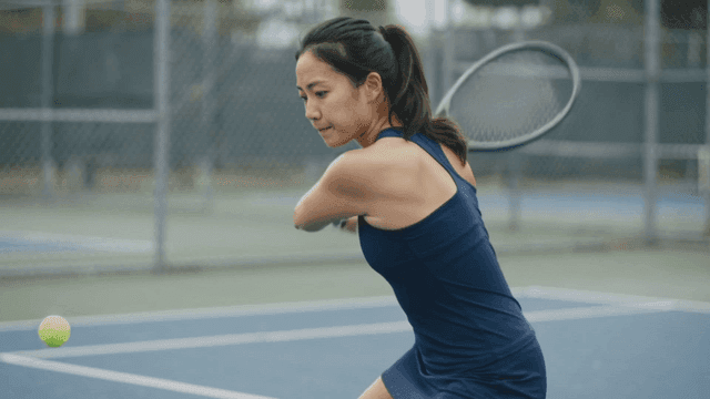 Woman playing tennis while focused on court