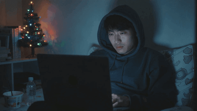 크리스마스 트리가 있는 어두운 방에서 노트북을 사용하는 젊은 남성