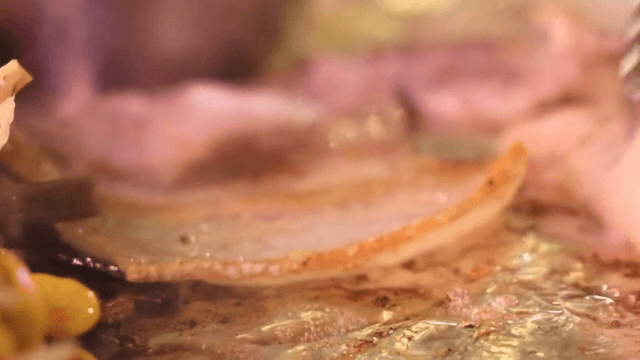 Sizzling frozen pork belly slices on a grill