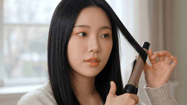 Woman styling her hair with a curling iron