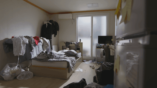 Person lying in a messy room with clothes and garbage