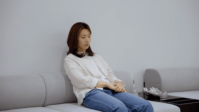 소파에 앉아 생각에 잠긴 여성