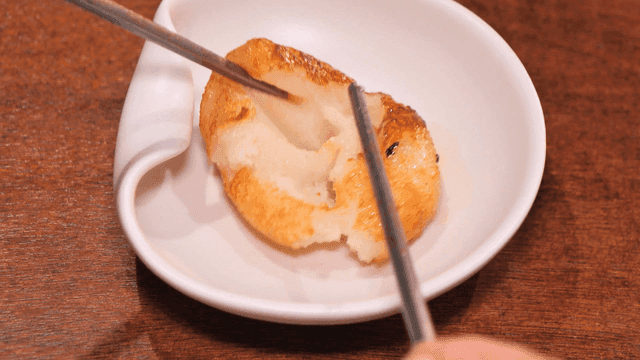 Fried food torn apart with chopsticks on white plate