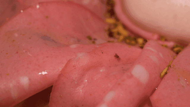 Mortadella pizza topped with pink meat slices and garnish