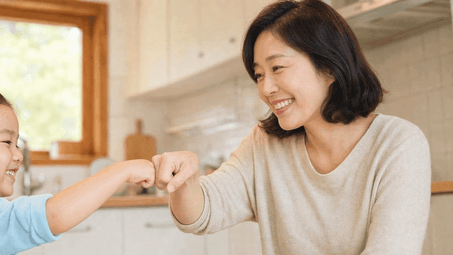 A mother and child fist bumping in the kitchen