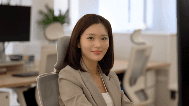 Female office worker smiling while looking straight ahead in office