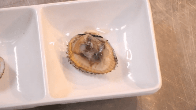 흰 접시에 담긴 꼬막 두개