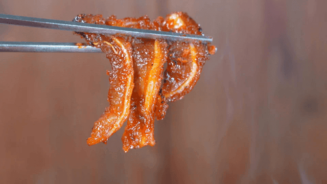 Spicy, crunchy braised pork ribs lifted with chopsticks