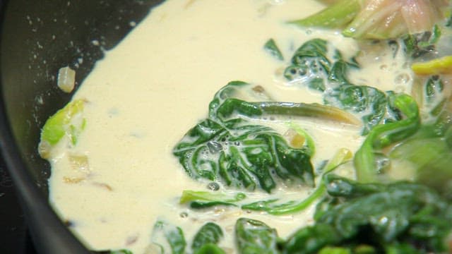 나무 주걱으로 우유와 함께 시금치를 볶기